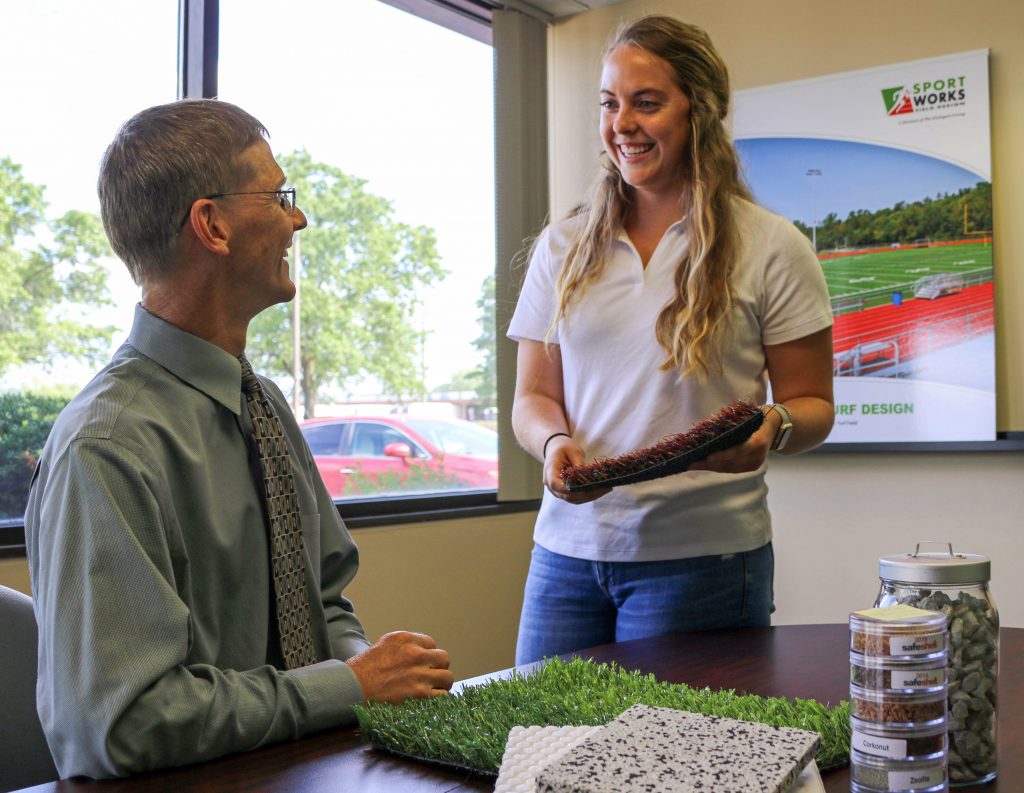 Kayleigh laughs with Craig, synthetic turf